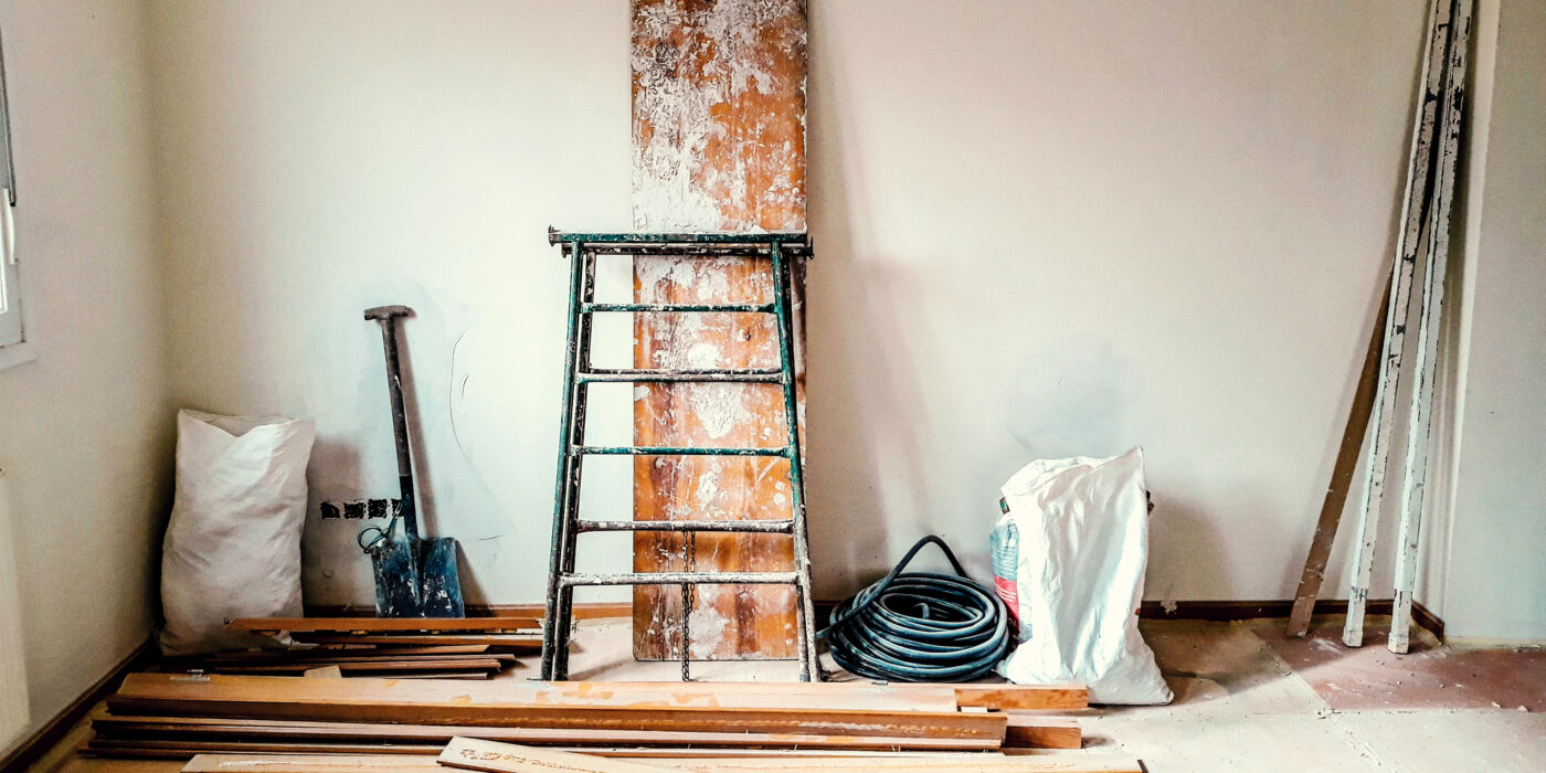 Reforma em uma sala com parede branca e materiais de construção.